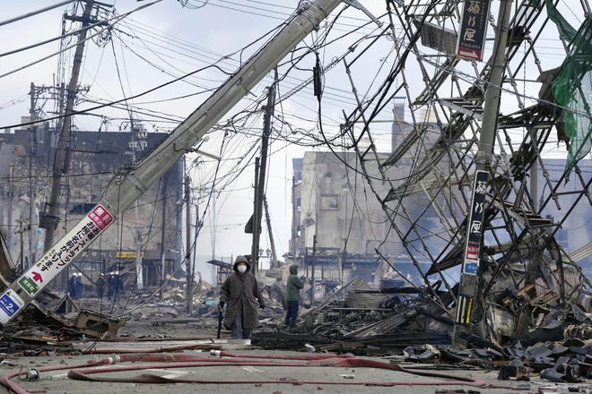 People walk through the damaged marketplace burnt by fire after earthquake in Wajima, Ishikawa prefecture, Japan Tuesday, Jan. 2, 2024.