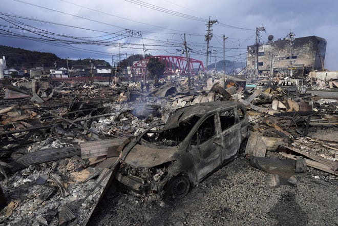A burned car and debris are seen at a marketplace after a fire following strong earthquake in Wajima, Ishikawa prefecture, Japan Tuesday, Jan. 2, 2024.