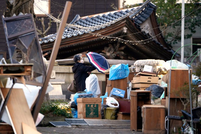 A person checks her belongings at a collapsed house damaged by a powerful earthquake in Anamizu in the Noto peninsula facing the Sea of Japan, northwest of Tokyo, Thursday, Jan. 4, 2024. More soldiers have been ordered to bolster the rescue operations Thursday, providing those in need with drinking water hot meals and setting up bathing facilities after a magnitude 7.6 quake hit Ishikawa Prefecture and nearby regions Monday.