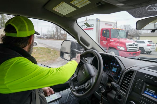 Dustin Brown navigates the entrance to North Michigan Road on Thursday, Jan. 4, 2024, on the northwest side of Indianapolis during a day of delivering firewood. He and an assistant are heading out to deliver four ricks of wood.